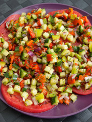 Tomatoes with salsa salad made of cucumbers, peppers and onions. Shot from above, vertical view.