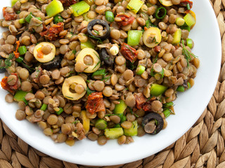 Lentil salad with green peppers, dried tomatoes and olives. Cropped, shot from above