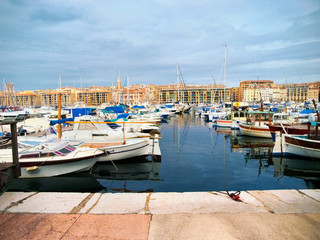 Yachts and boats in the port of Marseille, France on a cloudy day. Wide angle shot with buildings on background