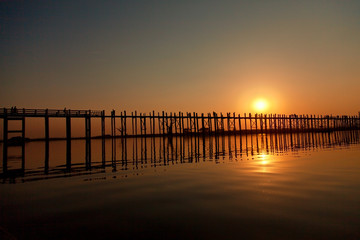 U Bein Bridge at sunset with people crossing Ayeyarwady River, Mandalay, Myanmar. Wide angle shot