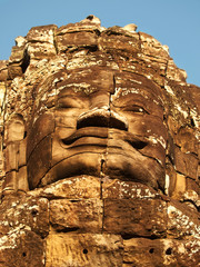 Dramatic view at sunset of one of the many large stone carved faces of Bayon Temple in Angkor Thom, Angkor district, Siem Reap, Cambodia. Vertical shot