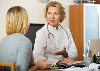 Elderly physician doing check up of sick female patient