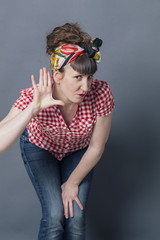 communication problem - deaf-like retro style woman leaning forward with hand on ear to understand louder,gray background studio.