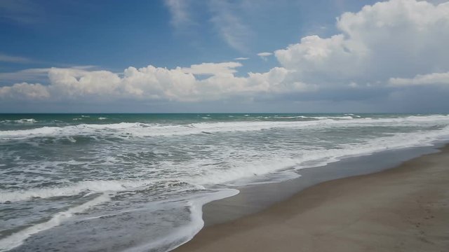 A dramatic cloudy blue skies tops the Atlantic Ocean as waves break on a sandy beach in Florida.