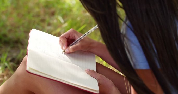 Mixed Race Person sitting at tree writing in journal