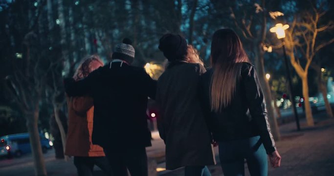 Teen hipster friends enjoying a night walk in the city
