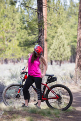Fototapeta premium Woman riding mountain bike on trail in forest