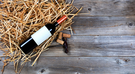 Red wine bottle with vintage wine corkscrew on straw 