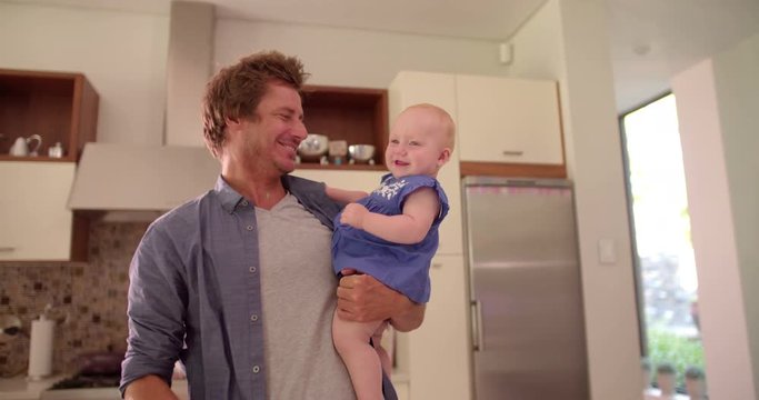 Modern Dad Holding and Kissing Infant Daughter on Cheek