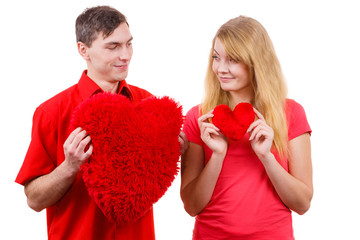 Couple holds red heart shaped pillows love symbol