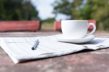 coffee cup and pen on newspaper selective focus