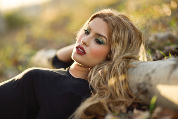 Fototapeta premium Relaxed girl lying on the field with long curly hair.