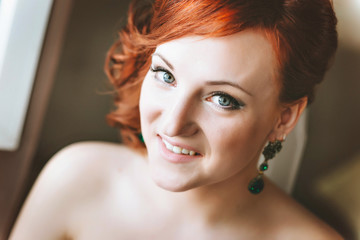 portrait of red-haired young woman bride, smiling, looking at the camera