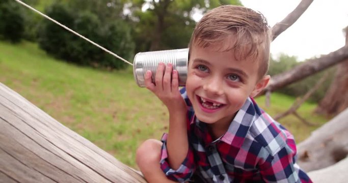 Cute little Boy curiously listening on tin can phone in park