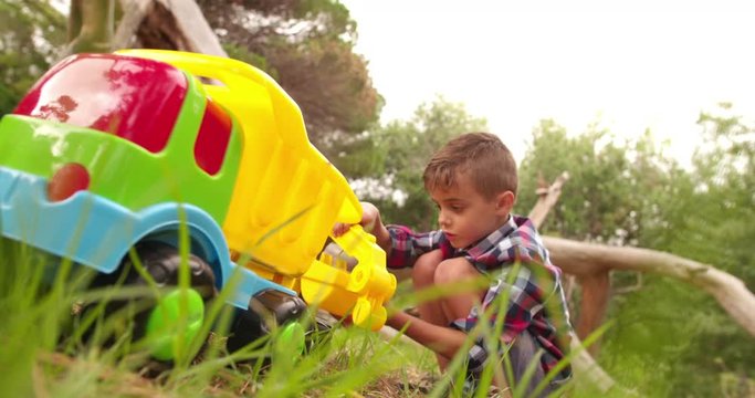 Boy playing and digging with toy excavator in garden
