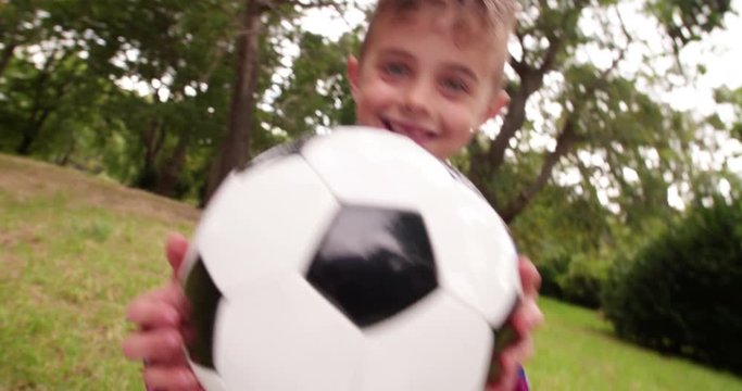 Excited little holding football in hands and is smiling