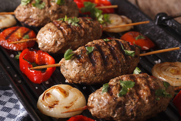Kofta kebabs with vegetables closeup on a grill pan. horizontal
