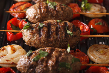 Kyufta kebabs with vegetables macro on a grill pan. horizontal

