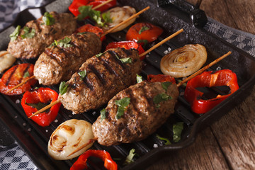 Kyufta kebabs with vegetables close-up on a grill pan. horizontal
