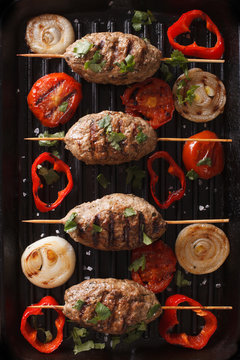 Kofta kebab with grilled vegetables on grill close-up. vertical top view
