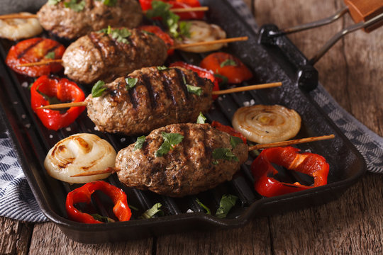 Kyufta kebab with grilled vegetables closeup on a grill pan. horizontal
