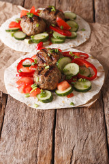 Grilled meat balls with fresh vegetables on a flat bread close up. Vertical
