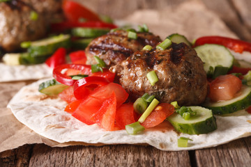Turkish kofta with fresh vegetables on a flat bread close up. horizontal
