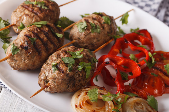 Kofta kebab with grilled vegetables on a plate close-up. horizontal
