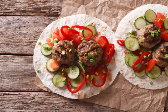 Grilled meat balls with fresh vegetables on a flat bread. Horizontal top view
