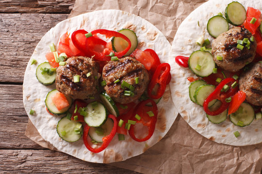 Grilled meat balls with fresh vegetables on a flat bread closeup. horizontal top view
