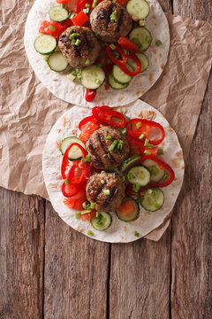 Grilled meat balls with fresh vegetables on a flat bread. Vertical top view
