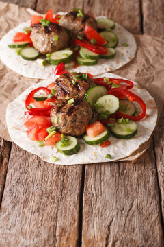 Grilled meat balls with fresh vegetables on a flat bread close up. Vertical
