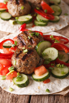 Turkish kofta with fresh vegetables on a flat bread close up. Vertical
