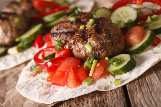 Meatballs with fresh vegetables on a tortilla close-up. horizontal

