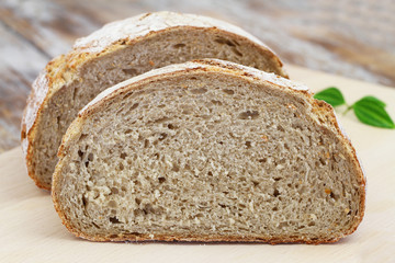 Rye bread cut in half on wooden board, closeup

