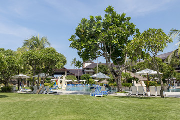 Kuta Beach palm coat, luxury resort with swimming pool and sunbeds. Bali, Indonesia