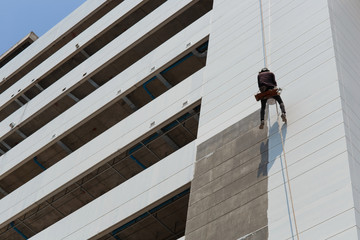 Worker painting high rise building in construction site.High risk working concept. © arcyto