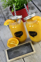 Gläser mit Obstsaft mit Tafel auf rustikalem Tisch