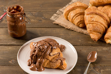 Breakfast croissant with chocolate on a rustic background