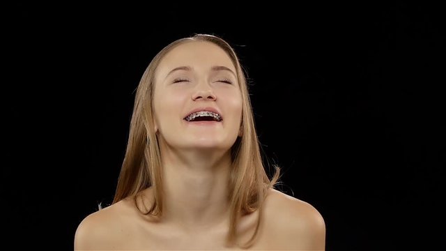 Woman laughs and shows her smile with braces. Black. Slow motion