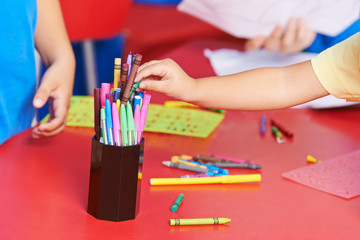 Hand eines Kindes nimmt Wachsmalstift