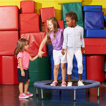 Kinder springen auf Trampolin in Turnhalle