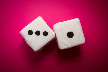 Pair of white plush dices on the pink background