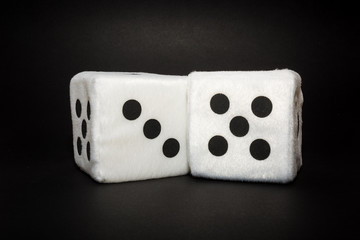 Pair of white plush dices on the black background