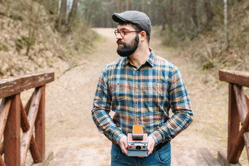 Young man bearded with film photocamera in the forest