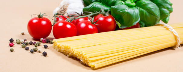 Raw pasta and ingredients for pasta with tomatoes and basil.