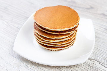 Fototapeta na wymiar Tasty pancake on a white plate, wooden background, maple syrup