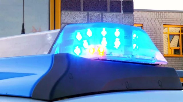 Anhaltestab vor Einsatzfahrzeug der Polizei mit Blaulicht
