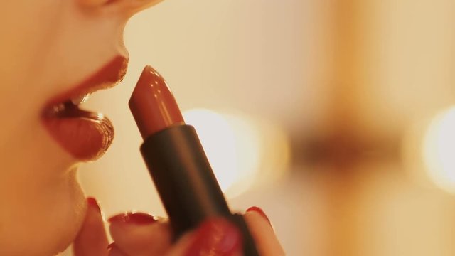 Extreme close up on model applying dark red lipstick