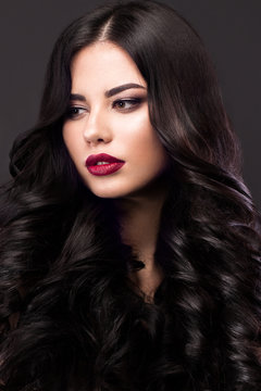 Beautiful brunette model: curls, classic makeup and red lips. The beauty face. 
